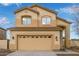 Two-story tan home featuring an attached garage, arched entrance, and well-maintained landscaping at 2834 N Paisley Ln, Casa Grande, AZ 85122