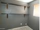 A gray bedroom featuring wooden shelving and a window for natural light at 3618 W Las Palmaritas Dr, Phoenix, AZ 85051