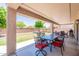 This home has a covered patio with a dining set overlooking the well-manicured lawn at 5445 S 239Th Dr, Buckeye, AZ 85326