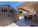 A spacious backyard featuring a covered patio, dining set, well-maintained lawn, and a storage shed at 5445 S 239Th Dr, Buckeye, AZ 85326
