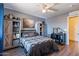 Cozy bedroom features wood-look floors, ceiling fan, rustic furnishings, shelving, and a desk area at 5445 S 239Th Dr, Buckeye, AZ 85326