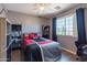 This bedroom has a ceiling fan, window, and a display shelf with a black office chair at 5445 S 239Th Dr, Buckeye, AZ 85326