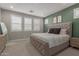 Spacious bedroom with carpet floors, green accent wall, and window shutters at 7442 W Redbird Rd, Peoria, AZ 85383