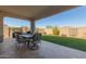 Relaxing covered patio with an outdoor dining set and lush green backyard at 7442 W Redbird Rd, Peoria, AZ 85383