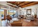 Bright living room features terracotta flooring, ceiling fans, exposed wood beams, and large windows overlooking backyard at 8540 E Mcdowell Rd # 19, Mesa, AZ 85207