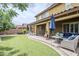 Backyard featuring artificial turf, lush landscaping, and covered patio with ample seating at 10249 E Kinetic Dr, Mesa, AZ 85212