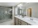 Bright bathroom featuring double sinks, large mirror, decorative accents, and tiled glass shower at 10249 E Kinetic Dr, Mesa, AZ 85212