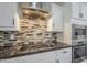 Close up of kitchen counter with stainless cooktop, stainless oven, and tile backsplash at 10249 E Kinetic Dr, Mesa, AZ 85212
