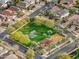 Aerial view of a neighborhood park featuring a green lawn, trees, and a playground at 10249 E Kinetic Dr, Mesa, AZ 85212