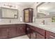 Bathroom with double vanity sinks, framed mirrors, and dark wood cabinetry at 10410 E San Tan Blvd, Sun Lakes, AZ 85248