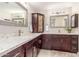 Bathroom with double vanity sinks, framed mirrors, and dark wood cabinetry at 10410 E San Tan Blvd, Sun Lakes, AZ 85248