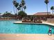 Large community pool surrounded by lounge chairs and lush tropical landscaping on a sunny day at 10410 E San Tan Blvd, Sun Lakes, AZ 85248