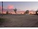 Image showcasing a lush green golf course surrounded by trees during a colorful sunset at 11005 W Crestbrook Dr, Sun City, AZ 85351