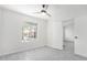 Bright bedroom featuring a ceiling fan, light gray floors, a large window, and white door at 13238 W Market St, Surprise, AZ 85374