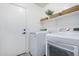 Modern laundry room with white washer and dryer, floating shelves, and decor at 13238 W Market St, Surprise, AZ 85374