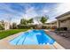 In-ground pool with lush landscaping, patio seating, and a blue sky at 13238 W Market St, Surprise, AZ 85374