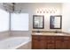 Bathroom featuring a soaking tub, double vanity with granite countertop and decorative lighting at 1363 E Amberwood Dr, Phoenix, AZ 85048