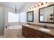 Bathroom featuring a soaking tub, double vanity with granite countertop and decorative chandelier at 1363 E Amberwood Dr, Phoenix, AZ 85048