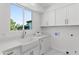 Bright laundry room with white cabinetry, a large window, and stone counter tops at 1523 E Treasure Cove Dr, Gilbert, AZ 85234