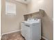 Bright laundry room featuring full-size washer and dryer and a storage shelf at 18268 W Carol Ave, Waddell, AZ 85355