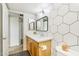 Modern bathroom with a wood vanity cabinet, black mirror, and stylish hexagon tile accent wall at 2117 W Pontiac Dr, Phoenix, AZ 85027