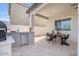 Covered patio with an outdoor kitchen, dining table, and travertine tile flooring at 21186 W Hillcrest Blvd, Buckeye, AZ 85396