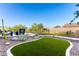 Landscaped backyard featuring artificial turf, stone features and a raised patio sitting area at 21186 W Hillcrest Blvd, Buckeye, AZ 85396