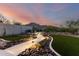 Inviting backyard features a stone pathway, artificial turf, and outdoor seating with mountain views at sunset at 21186 W Hillcrest Blvd, Buckeye, AZ 85396