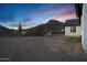 Rear view of a home with sunset sky, mountain views, storage shed and desert landscape at 2438 N 113Th St, Mesa, AZ 85207