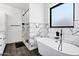 Modern bathroom featuring a soaking tub, glass enclosed shower, and marble tile accents at 2438 N 113Th St, Mesa, AZ 85207