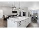 A modern kitchen features an island with a marble countertop, white cabinets, and stainless steel appliances, flowing into the living area at 2438 N 113Th St, Mesa, AZ 85207