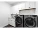 Well-lit laundry room with modern appliances, white cabinets, and dark wood flooring at 2438 N 113Th St, Mesa, AZ 85207