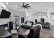 Spacious living room with leather furniture, a modern ceiling fan, and an adjacent kitchen featuring white cabinets at 2438 N 113Th St, Mesa, AZ 85207