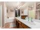 Bathroom featuring double sinks, a soaking tub, and decorative mirrors at 25732 W St James Ave, Buckeye, AZ 85326