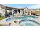 Stunning backyard featuring a pool, spa, covered patio, lounge seating, and a built-in fire pit, perfect for outdoor living at 303 S 197Th Ave, Buckeye, AZ 85326