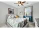 Cozy bedroom featuring a patterned bedspread, ceiling fan, and natural light from a window with teal curtains at 303 S 197Th Ave, Buckeye, AZ 85326