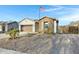 A single-story home with neutral stucco, stone accents, desert landscaping, and a two car garage at 303 S 197Th Ave, Buckeye, AZ 85326