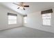 Carpeted primary bedroom with ceiling fan, white walls, and three large windows at 31555 N Royce Rd, San Tan Valley, AZ 85144