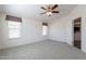 Spacious bedroom with light gray carpet, a ceiling fan, and three windows at 31555 N Royce Rd, San Tan Valley, AZ 85144