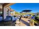 Covered patio featuring a dining area, pool views, comfortable seating under blue umbrellas, and lush desert landscaping at 31709 N 16Th Ave, Phoenix, AZ 85085