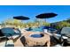 Outdoor seating area with a stone fire pit and desert landscaping located near a sparkling blue pool and blue umbrellas at 31709 N 16Th Ave, Phoenix, AZ 85085