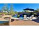 Outdoor living area with a custom grill, a waterfall feature near the pool, seating, and a view of desert landscaping at 31709 N 16Th Ave, Phoenix, AZ 85085