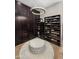 Elegant walk-in closet featuring custom dark wood cabinets, shelving, a soft rug and a modern chandelier at 3246 E San Miguel Pl, Paradise Valley, AZ 85253