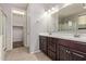 Bright bathroom features double sinks, dark wood cabinets, and a walk in closet with carpet at 3254 N Park St, Buckeye, AZ 85396