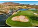 Picturesque aerial view of the golf course showcasing a serene lake, a cascading waterfall, and manicured greens at 41921 N Crooked Stick Rd, Anthem, AZ 85086