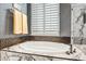 Relaxing bathroom with a large tub and a window with shutter, and decorative tile at 41921 N Crooked Stick Rd, Anthem, AZ 85086