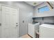 Bright laundry room featuring a side-by-side washer and dryer, a storage shelf and a closed white door at 41921 N Crooked Stick Rd, Anthem, AZ 85086