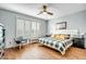 Bright main bedroom features wood floors, a ceiling fan, and large window dressed with stylish white shutters at 41921 N Crooked Stick Rd, Anthem, AZ 85086