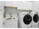 This laundry room features a white quartz countertop with a stainless steel sink and front loading washer and dryer at 4208 E Sells Dr, Phoenix, AZ 85018