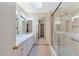 Bright bathroom with a double vanity, mirrored walls, and a shower/tub combo with glass doors at 4349 E Stanford Dr, Phoenix, AZ 85018